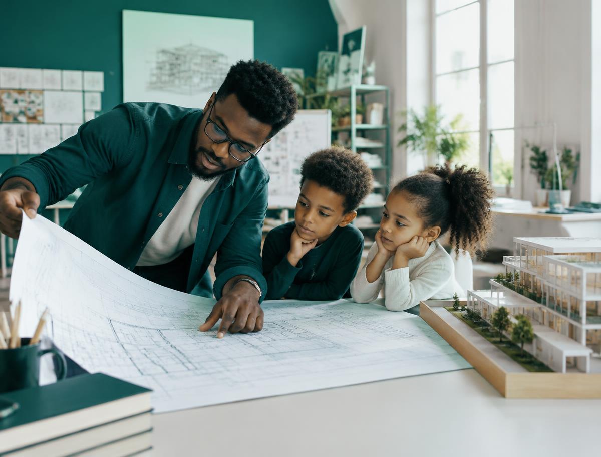 An architect showing building blueprints to two elementary students at a studio table
